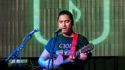 a singer performs on stage, whilst playing the guitar