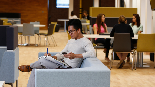 Person sat on sofa with phone and notepad